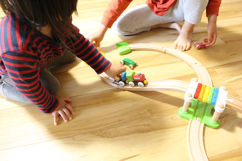 木製の鉄道おもちゃで姉妹が遊んでいるところ